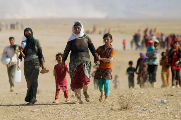 Displaced people from the minority Yazidi sect, fleeing violence from forces loyal to the Islamic State in Sinjar town, walk towards the Syrian border, on the outskirts of Sinjar mountain, near the Syrian border town of Elierbeh of Al-Hasakah Governorate August 11, 2014. Islamic State militants have killed at least 500 members of Iraq's Yazidi ethnic minority during their offensive in the north, Iraq's human rights minister told Reuters on Sunday. The Islamic State, which has declared a caliphate in parts of Iraq and Syria, has prompted tens of thousands of Yazidis and Christians to flee for their lives during their push to within a 30-minute drive of the Kurdish regional capital Arbil. Picture taken August 11, 2014. REUTERS/Rodi Said (IRAQ - Tags: CIVIL UNREST POLITICS SOCIETY)